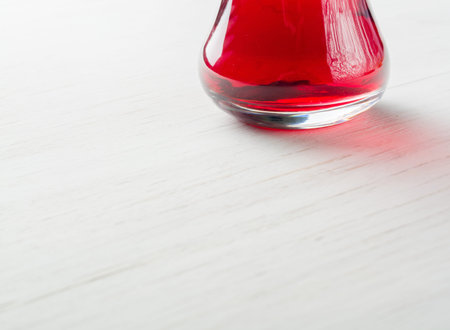 Hibiscus tea in a glass mug on a wooden table among rose petals and dry tea custard. Copy space.の写真素材