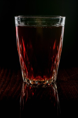 A glass with red drink on a dark background.の写真素材
