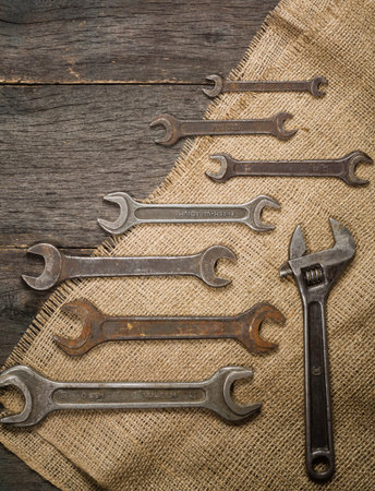 old and rusty spanners on a background of a wooden table and sacking. Space for text.