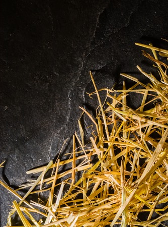 A bunch of yellow straw on the black background of an empty slab of slate. Place for text.の写真素材