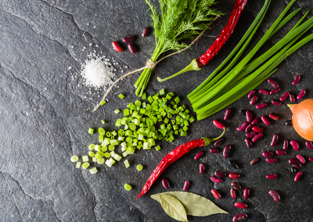 Arrangement of chives, onions, beans and dill on a black background stone slate. View from above.の写真素材