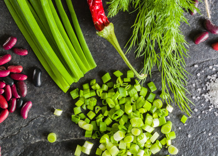 Arrangement of chives, onions, beans and dill on a black background stone slate. View from above.の写真素材
