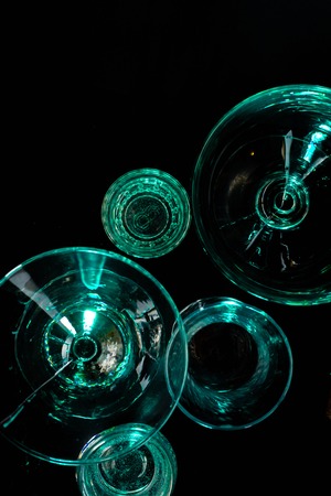 Glasses and glasses highlighted by colored light on a black background. Low key.の写真素材