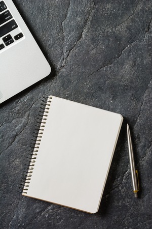 Laptop, pen and notebook with a spring on a black background. Clean page. Place for the text.の写真素材