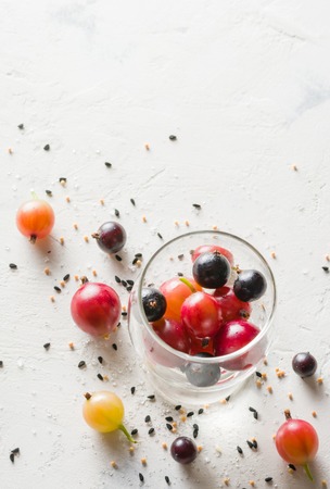 Gooseberries and black currants on a white background in a transparent glass. A lot of empty space.の写真素材