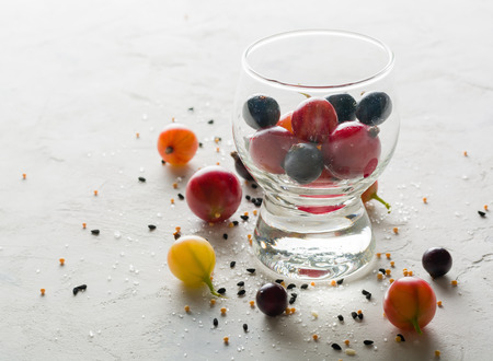 Gooseberries and black currants on a white background in a transparent glass. A lot of empty space.の写真素材