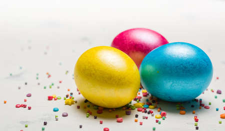 Easter background with multi-colored chicken eggs on a white stone slab. Place for the text.の写真素材