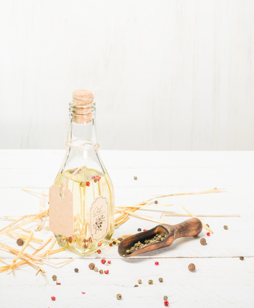 Vegetable oil in a bottle with seasonings and spices on a white wooden background.の写真素材