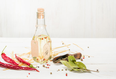 Vegetable oil in a bottle with seasonings and spices on a white wooden background.の写真素材