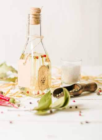 Vegetable oil in a bottle with seasonings and spices on a white wooden background. Place for the text.の写真素材