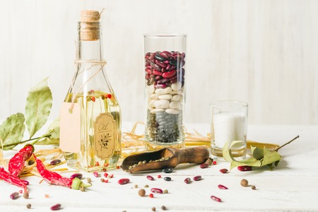 Vegetable oil in a bottle with seasonings and spices on a white wooden background. Place for the text.の写真素材