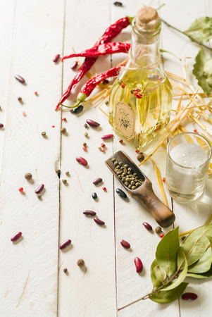 Vegetable oil in a bottle with seasonings and spices on a white wooden background. Place for the text.の写真素材