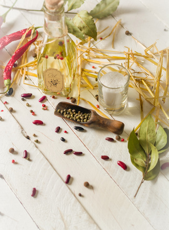 Vegetable oil in a bottle with seasonings and spices on a white wooden background. Place for the text.の写真素材
