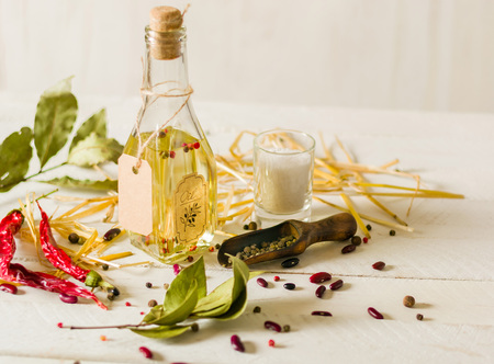 Vegetable oil in a bottle with seasonings and spices on a white wooden background. Place for the text.の写真素材
