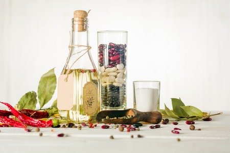 Vegetable oil in a bottle with seasonings and spices on a white wooden background. Place for the text.の写真素材