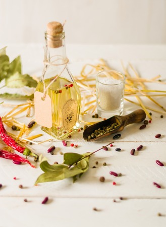 Vegetable oil in a bottle with seasonings and spices on a white wooden background. Place for the text.の写真素材