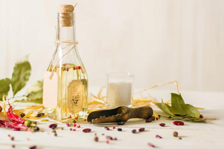 Vegetable oil in a bottle with seasonings and spices on a white wooden background. Place for the text.の写真素材
