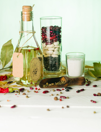 Vegetable oil in a bottle with seasonings and spices on a white wooden background. Place for the text.の写真素材