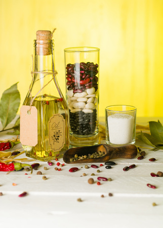 Vegetable oil in a bottle with seasonings and spices on a white wooden background. Place for the text.の写真素材
