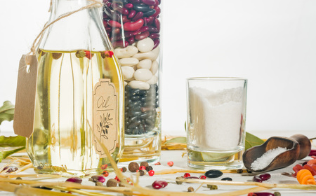 Vegetable oil in a bottle with seasonings and spices on a white wooden background. Place for the text.の写真素材