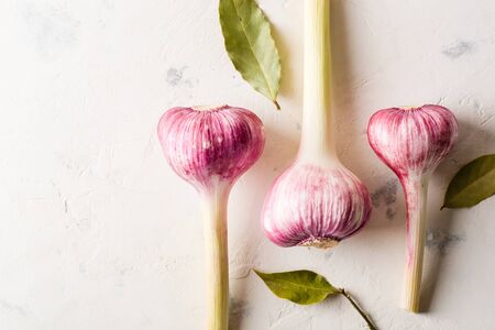 Garlic purple with stem on a white stone background. A lot of empty space.の写真素材