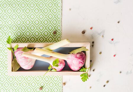 Garlic purple with Parsley in wooden box on a white stone background. A lot of empty space.の写真素材