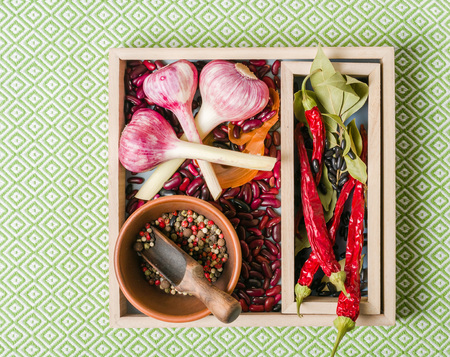 Garlic purple with pepper and beans in wooden box on a white stone background. A lot of empty space.の写真素材