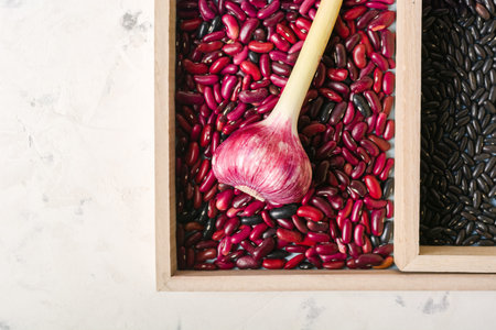 Garlic purple and beans in wooden box on a white stone background. A lot of empty space.の写真素材
