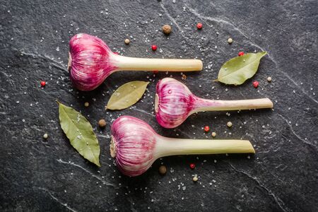 Garlic purple with stem on a black stone background. A lot of empty space.の写真素材