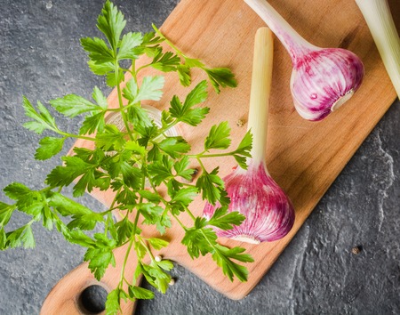 Fresh parsley and garlic on cutting board. Black stone background.の写真素材