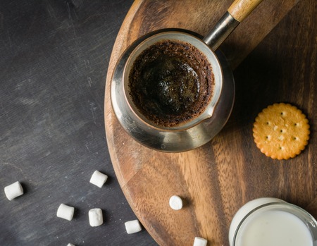 Morning coffee with marshmallows, cookies and milk. Dark wooden background. Place for the text.の写真素材