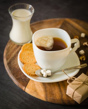 Morning coffee with marshmallows, cookies and milk. Dark wooden background. Place for the text.の写真素材