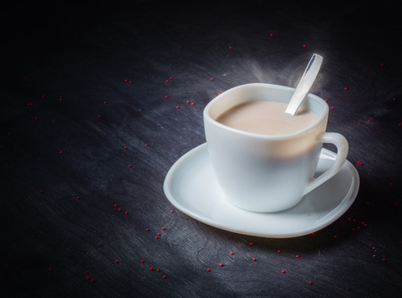 White cup on a saucer with hot cocoa. Morning breakfast. Dark wooden background.の写真素材