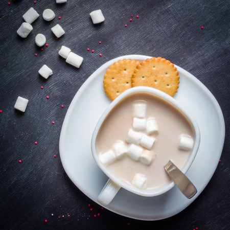 White cup on a saucer with hot cocoa. Morning breakfast. Dark wooden background.の写真素材