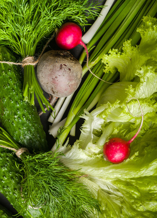 Variety of vegetables on a black wooden table. Spring still life. View from above.の写真素材