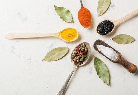 Spices in different spoons on a stone white background. High key.の写真素材
