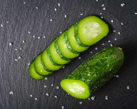 Fresh green sliced cucumber on a black stone background. Copy space.の写真素材