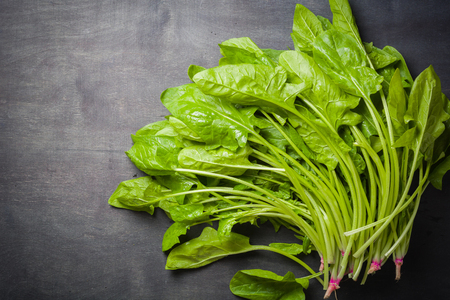 A large stack of fresh and green Leaves spinach on a black wooden background. Place for the text. View from above.の写真素材