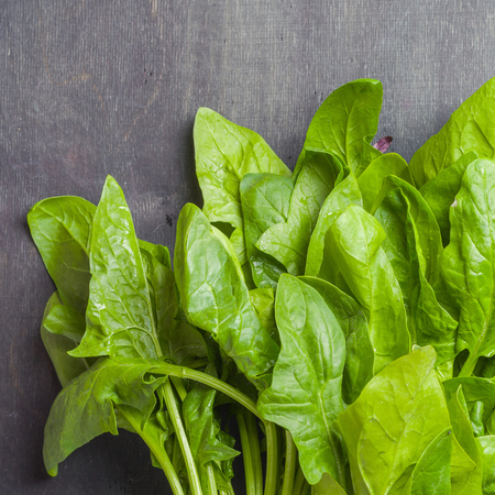 A large stack of fresh and green Leaves spinach on a black wooden background. Place for the text. View from above.の写真素材