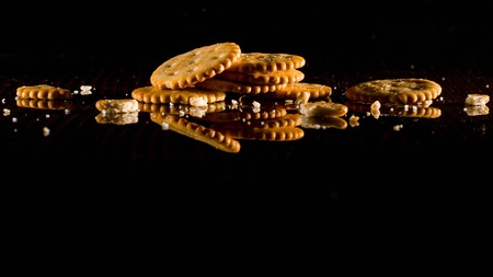 A stack of cookies and crumbs on a dark glossy background. Copy space.の写真素材