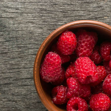 Ripe juicy berries of raspberry and clay bowl. View from above. Copy space.の写真素材