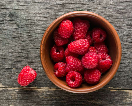 Ripe juicy berries of raspberry and clay bowl. View from above. Copy space.の写真素材
