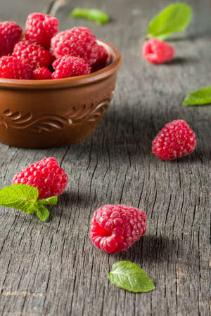 Ripe juicy raspberries on a dark background. Fresh green mint leaves. View from above.の写真素材