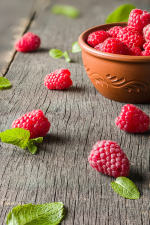 Ripe juicy raspberries on a dark background. Fresh green mint leaves. View from above.の写真素材