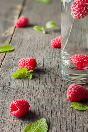 Ripe juicy raspberries on a dark background. Fresh green mint leaves. View from above.の写真素材