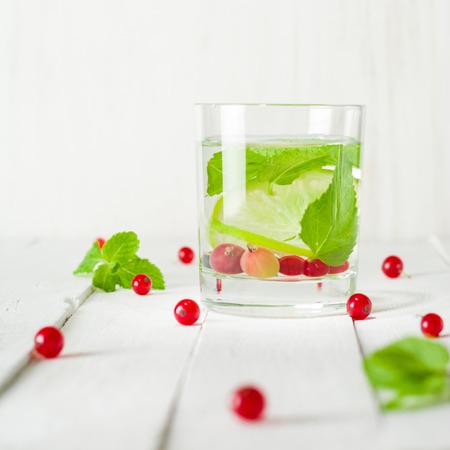 Detox water in a glass beaker. Berries and lime, red and green. Fresh mint leaves. Bright white background. Copy space.の写真素材