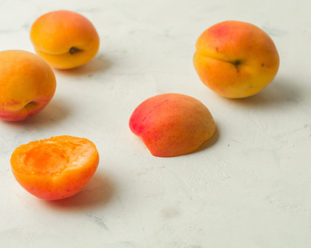 Fresh and ripe apricots on a white stone background.