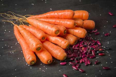 Carrots of various sizes stacked in a pile on a black wooden background. Washed and ready to eat.の写真素材
