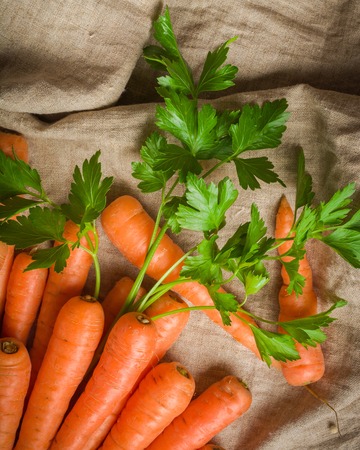 Carrots of various sizes stacked in a pile on a burlap background. Washed and ready to eat.の写真素材