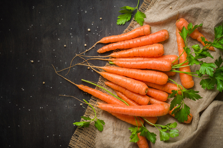 Carrots of various sizes stacked in a pile on a burlap background. Washed and ready to eat. View from aboveの写真素材